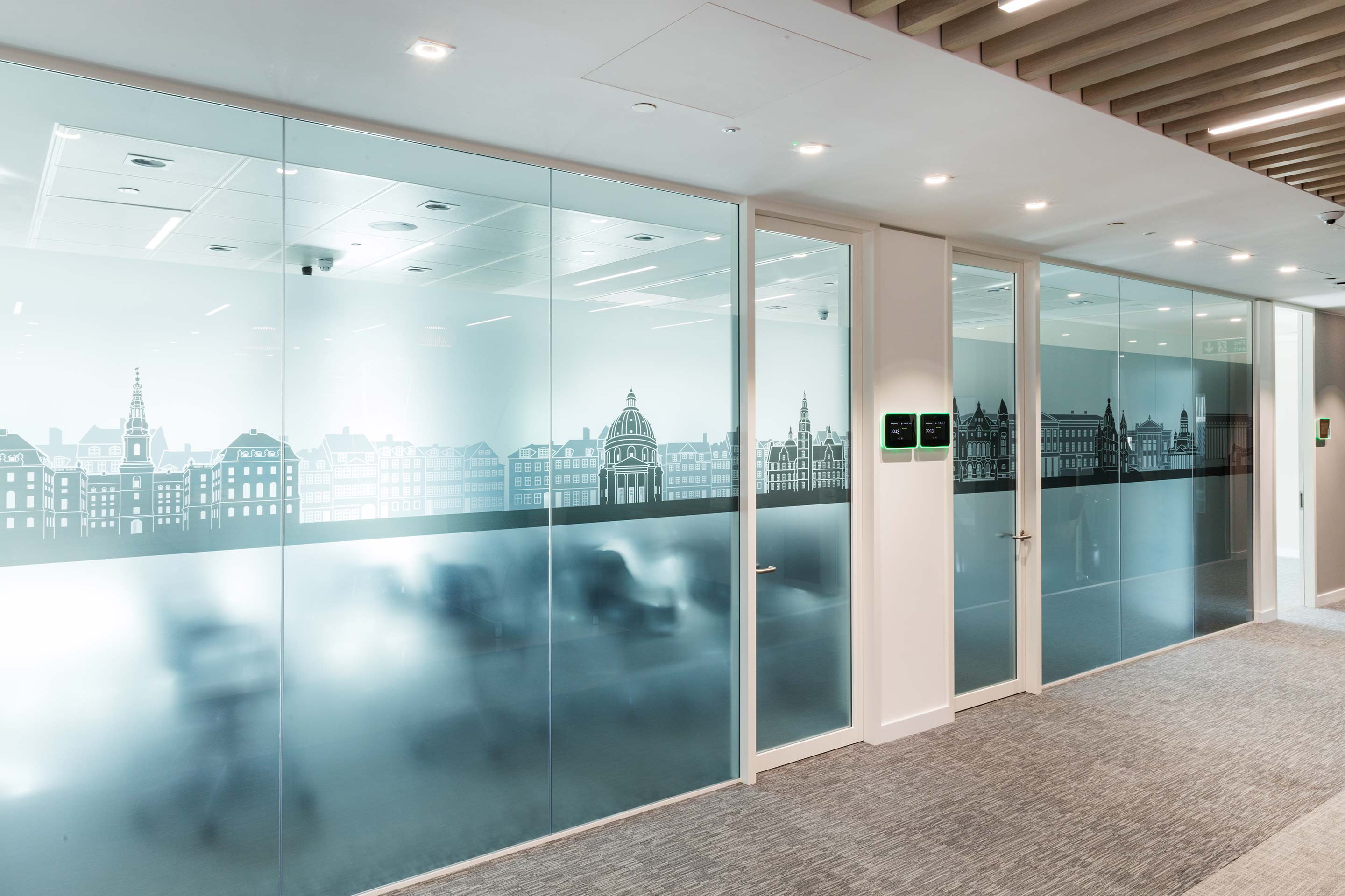 Modern office hallway with frosted glass doors featuring city skyline graphics.