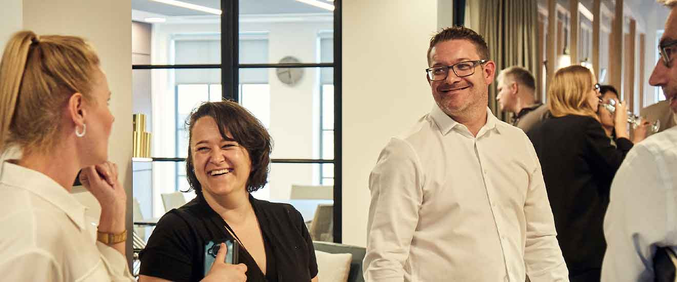Professionals conversing in Peldon Rose office, including Danielle Emery and Kevin Wither.