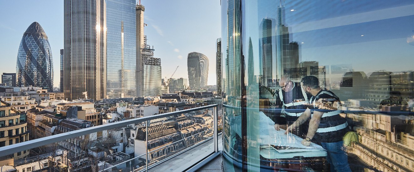 A panoramic view of a city skyline from a glass balcony with modern buildings.