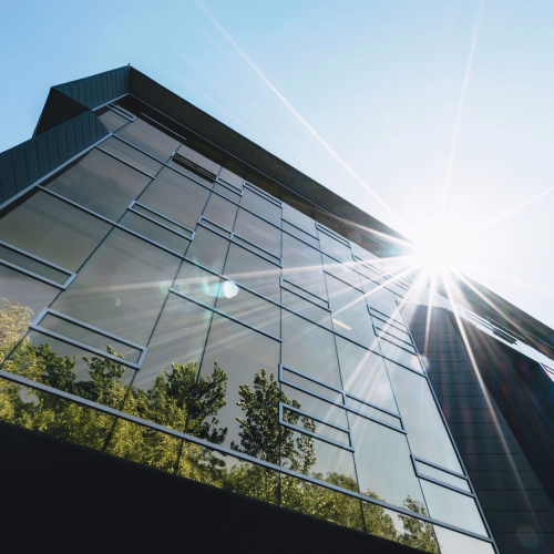 Modern building facade with reflective glass and sun flare.