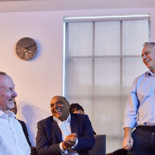 Three men laughing together in an office at a presentation.