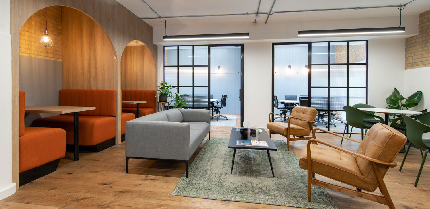 Open plan office with orange booth seating with Scandi chairs and biophilia