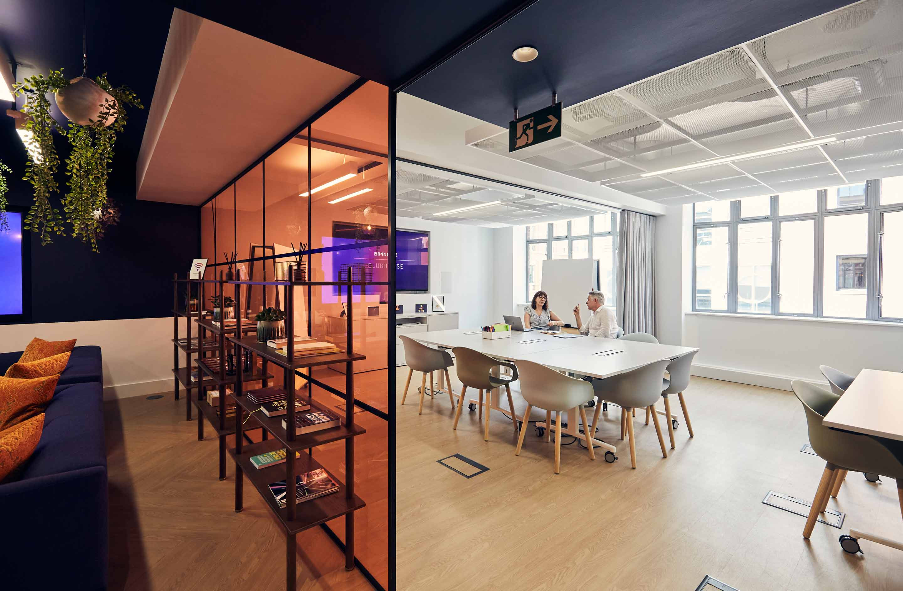 Open plan office with people collaborating and crittall glass partition with shelving