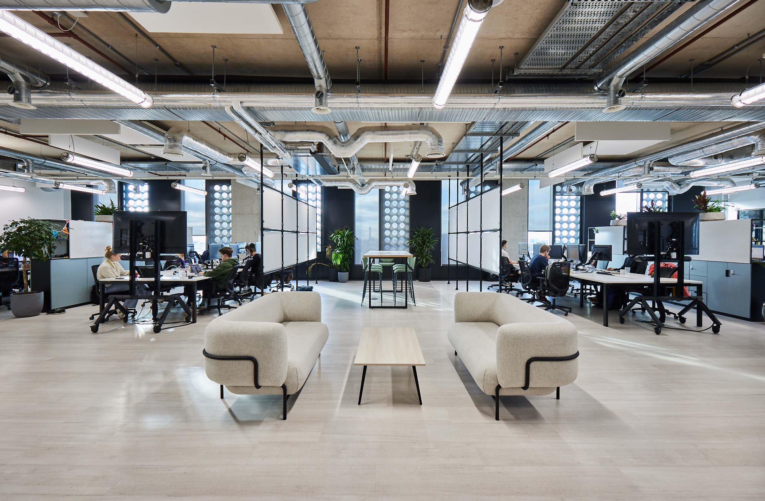 Brainlabs bright office space featuring a minimalist seating area with two cream sofas in front of office desks.