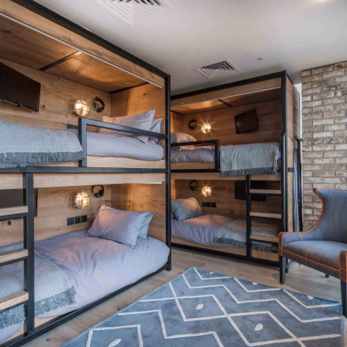 Modern rustic bunk beds in a chic room with wooden panels and stone wall.